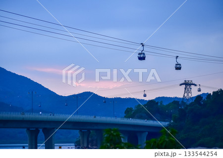 The scene of Cable Car in Hong Kong under the sunset from the view of Tung Chung, Hong Kong. It is one of transportations to the tourist attractions located at Ngong Ping, Lantau Island, in Hong Kong. 133544254