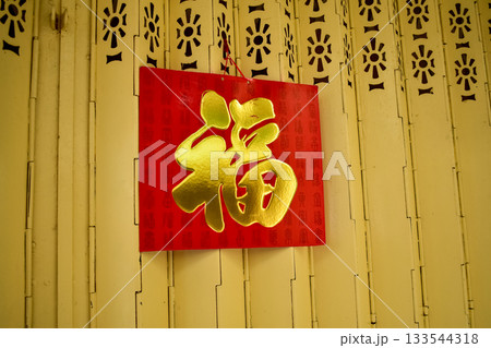 A chinese traditional calendar hanging on the iron door gate. Traditional practice to hang a big red calendar on the door for decoration. Translation: Luck. 133544318