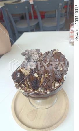 Decadent chocolate ice cream sundae with brownie pieces, nut sprinkle and creamy drizzle, indulgent dessert moment Decadent chocolate ice cream sundae with brownie pieces, nut sprinkle and creamy drizzle, indulgent dessert moment 133546512