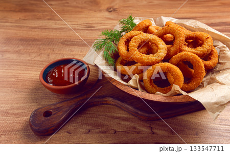 Deep fried onion rings, appetizer, with tomato sauce, on a wooden table, no people, favorite dish, 133547711