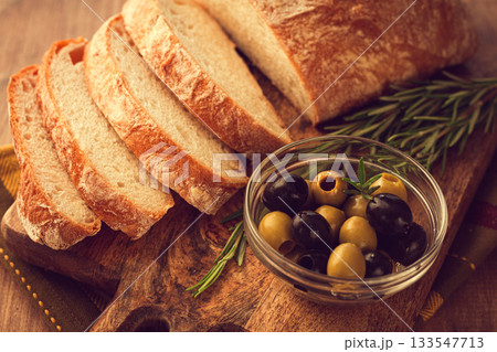 sliced ciabatta , on a chopping board, with rosemary and olives, Italian bread, close-up, Italian cuisine, breakfast, no people, 133547713