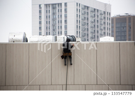 Industrial climber using his phone at work. Looking at phone during workday. Man distracted by his phone during dangerous work. Concept of people using phones, gadget addiction Industrial climber using his phone at work. Looking at phone during workday. Man distracted by his phone during dangerous work. Concept of people using phones, gadget addiction 133547779