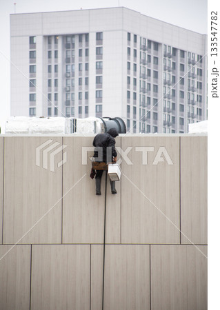 Industrial climber checks his toolbox before descending to working height. Industrial climber at work. This is extremely dangerous work in difficult weather conditions 133547782