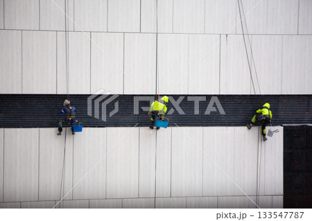 Team of industrial climbers working at height. Special suits and safety equipment for climbers. Photo of challenging moment involving risk of falling from height 133547787
