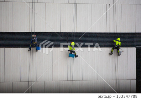The most dangerous job in the world. Workers at height clean buildings in harsh weather conditions. Dangerous combination of height and bad weather. Risk job, industrial climbers at work 133547789
