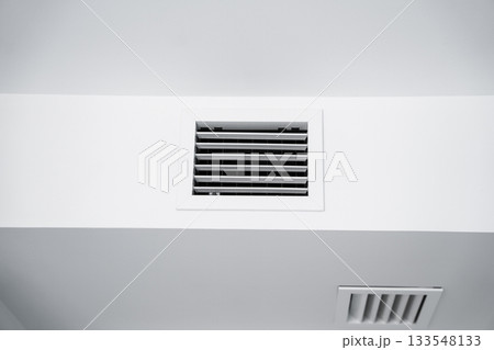 White ceiling ventilation grille with clean geometric lines in bright modern interior home environment White ceiling ventilation grille with clean geometric lines in bright modern interior home environment 133548133