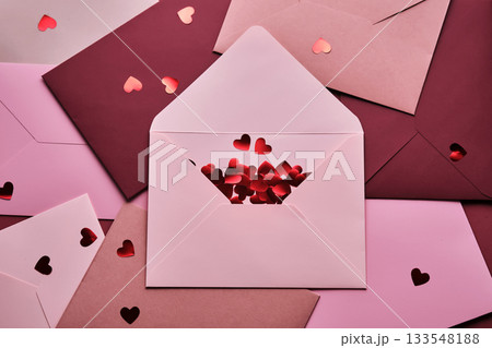 Scattering red heart confetti from a love letter envelope 133548188