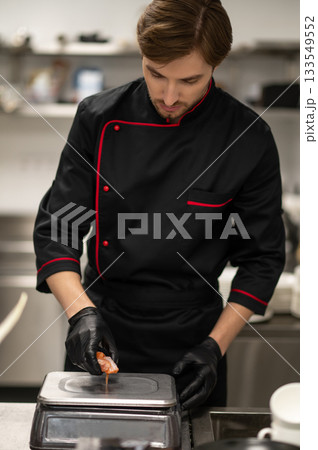Chef weighing pieces of salmon on kitchen scale 133549552
