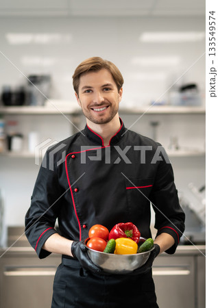Cook standing and holding dish with pepper cucumber and tomato 133549574