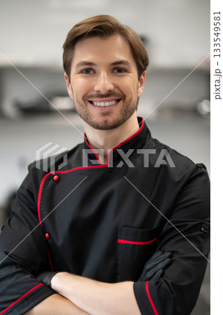 Chef standing with crossed arms in kitchen Chef standing with crossed arms in kitchen 133549581