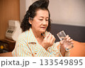 Grandma is taking medicine before going to bed. 133549895