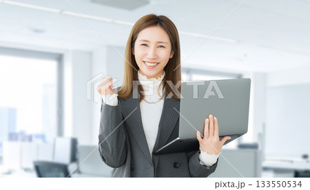 パソコンを持ってガッツポーズをする女性・ビジネスウーマン 133550534
