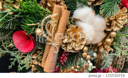 Christmas decor arrangement with cinnamon sticks golden pinecones red berries and green pine needles texture 133550758