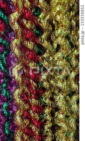 Abstract texture of wavy striped metallic tinsel garland in gold red green and purple for festive background 133550852