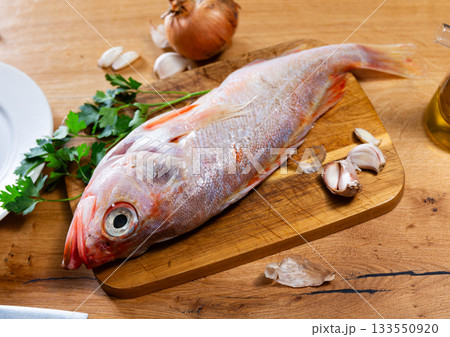 Raw whole red palometa fish with garlic and parsley on desk Raw whole red palometa fish with garlic and parsley on desk 133550920