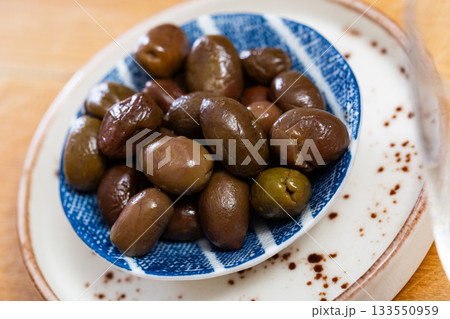 On white plate lies portion of large ripe green olives with stone. 133550959