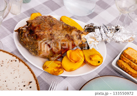 Traditional Spanish lunch is served - fried baked leg of lamb with side dish of potatoes Traditional Spanish lunch is served - fried baked leg of lamb with side dish of potatoes 133550972