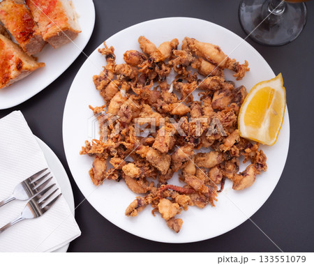 There is large portion of whole squid carcasses fried in batter in plate. There is large portion of whole squid carcasses fried in batter in plate. 133551079