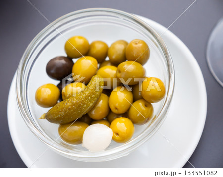 Bowl is filled with pickled vegetables - olives, small onions, gherkins Bowl is filled with pickled vegetables - olives, small onions, gherkins 133551082