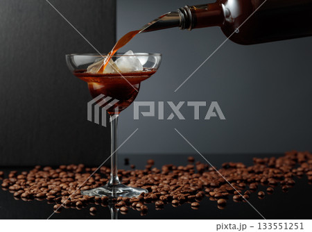 Coffee liquor is poured into a glass with ice. 133551251