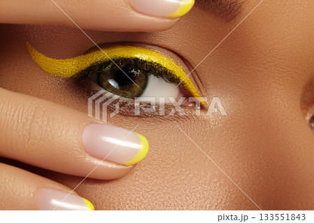 Close-up Female Eye with bright yellow Eyeliner Makeup. Neon Disco make-up and Fashion Manicure. Summer beauty style Close-up Female Eye with bright yellow Eyeliner Makeup. Neon Disco make-up and Fashion Manicure. Summer beauty style 133551843