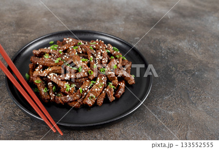 Fried teriyaki beef with sesame seeds and green onions on a brown background. Asian cuisine. Fried teriyaki beef with sesame seeds and green onions on a brown background. Asian cuisine. 133552555