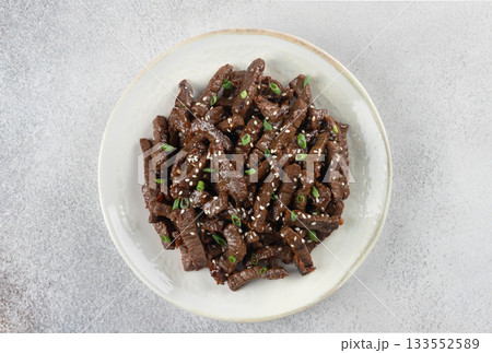Stir-fried teriyaki beef with sesame seeds on a gray background. Top view. Asian cuisine. Stir-fried teriyaki beef with sesame seeds on a gray background. Top view. Asian cuisine. 133552589