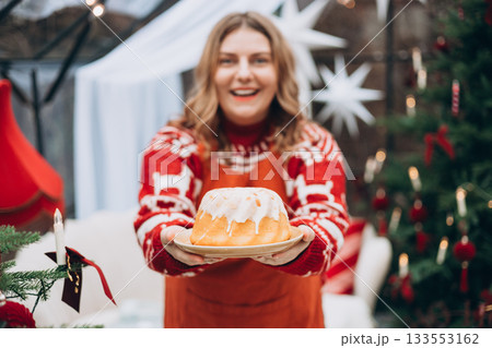 Lemon, vanilla marble bund cake in woman hands. Happy 30s girl standing near decorated Christmas tree. Winter time and holidays. Celebration banner, Lemon, vanilla marble bund cake in woman hands. Happy 30s girl standing near decorated Christmas tree. Winter time and holidays. Celebration banner, 133553162
