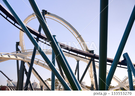 Interlacing loops and supports form an abstract network of steel. The modern roller coaster design stands out against a clear blue sky. 133553270