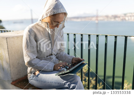 Woman working remotely on digital tablet outdoors in lisbon 133553338