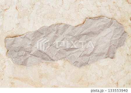 Torn piece of brown recycled paper on vintage spotted background. Contrast roughness in natural materials. Simple minimalist craft background, copy space Torn piece of brown recycled paper on vintage spotted background. Contrast roughness in natural materials. Simple minimalist craft background, copy space 133553940