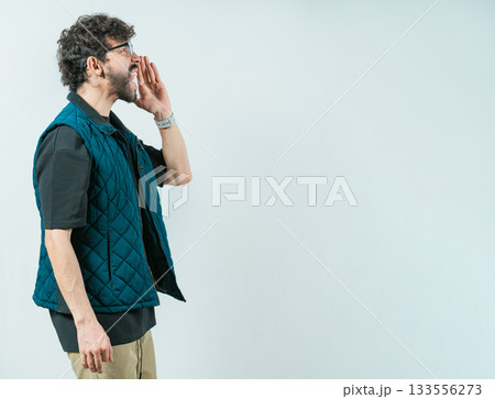 Casual young man in glasses shouting a promotion. Male person shouting an announcement isolated Casual young man in glasses shouting a promotion. Male person shouting an announcement isolated 133556273