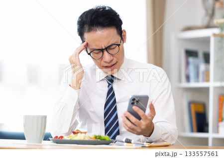 出勤前　スマホを見ながら食事をする男性 133557561