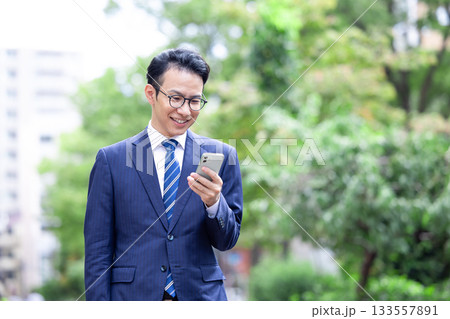 ビジネス　屋外　スマホを見ている男性 133557891