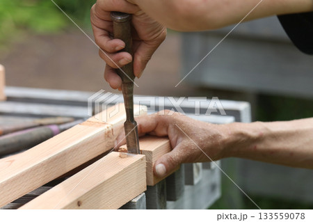 ノミで材木を削る男性 133559078