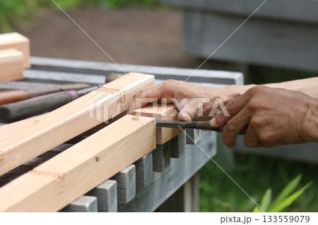 ノミで材木を削る男性 133559079