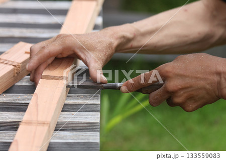 ノミで材木を削る男性 133559083