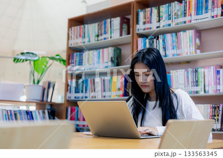 Asian female student working on laptop in modern library workspace 133563345