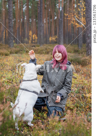 Girl training a dog in autumn forest with pink hair 133563706