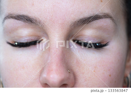 A woman has long extended eyelashes in a close-up with rhinestones. Preparing the image for the holiday A woman has long extended eyelashes in a close-up with rhinestones. Preparing the image for the holiday 133563847
