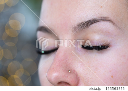 A woman has long extended eyelashes in a close-up with rhinestones. Preparing the image for the holiday 133563853