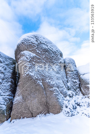 Wintertime rocks. Close-up view of granite rock covered by snow 133563919
