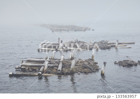 Landscape of a ruined wooden pier on the sea in fog Landscape of a ruined wooden pier on the sea in fog 133563957