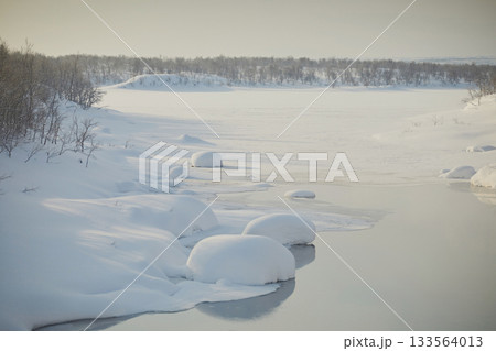 Freezing river with round snowdrifts and steam, close-up. Frosty day, northern winter landscape 133564013