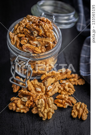 Peeled walnut kernels in jar on black table. 133565195