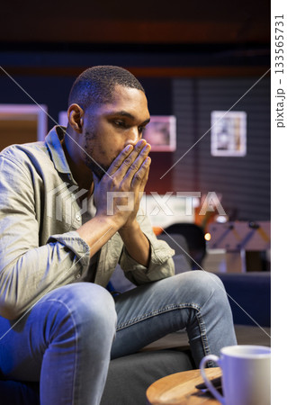Worried stressed black guy experiences fatigue and frustration at home, working remotely and struggling to meet deadlines. Young man fearing job failure, concerned remote worker. 133565731
