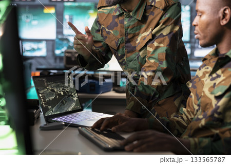 Army officers use reconnaissance tech on laptop to do threat monitoring and target recognition in command post. Military agents employing modern warfare intelligence using software on notebook 133565787