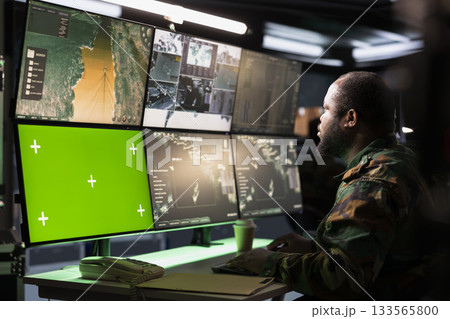 Army telecommunication systems agent using radio and satellite tech, providing combat support, watching mockup screens. Soldier managing communications networks, looking at chroma key monitors 133565800