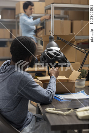 African american manager working on a laptop in a local warehouse depot, focusing on shipment logistics for order processing and local brand delivery service. Storage room tasks. 133565865