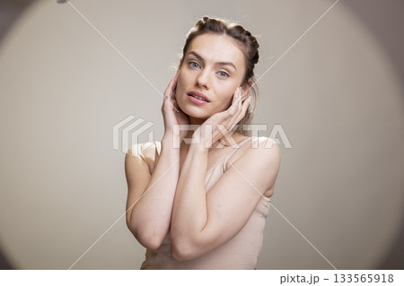 Female model posing with confidence for a cosmetics advertisement, wearing radiant natural makeup in the studio. Graceful positive expression embracing self acceptance and femininity. Female model posing with confidence for a cosmetics advertisement, wearing radiant natural makeup in the studio. Graceful positive expression embracing self acceptance and femininity. 133565918